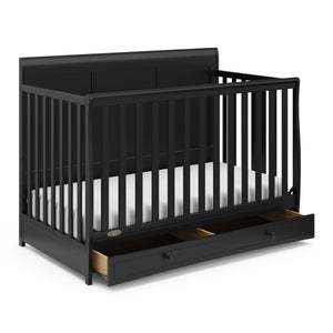 Angled view of black crib with open drawer 