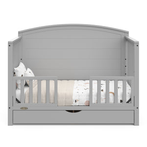  Convertible pebble gray crib transformed into a toddler bed with two guardrails