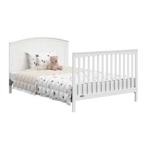 Convertible white crib transformed into a bed with headboard and footboard.
