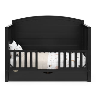 Convertible black crib transformed into a toddler bed with two guardrails