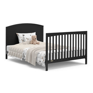 Convertible black crib transformed into a bed with headboard and footboard.