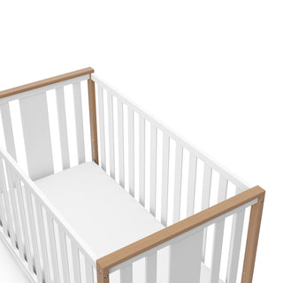 angled view of white crib with driftwood
