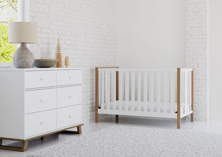 A serene nursery featuring a white and vintage driftwood crib accompanied by a matching 6-drawer dresser.