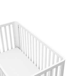 top view of a white crib with a natural wood color base