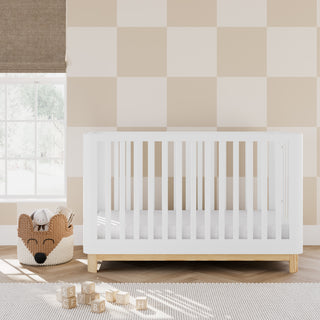 White crib with a natural wood color base in nursery