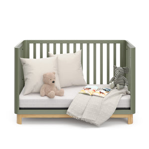 Front view of an olive crib with a natural wood color base in daybed conversion