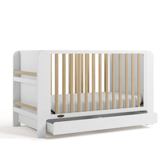 Two-tone white and natural wood baby crib with an open drawer and bookshelf sides