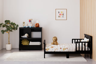 black toddler bed and changing table in nursery with multiple decorative elements