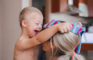 Happy smiling boy playfully placing striped article of clothing overtop woman's head