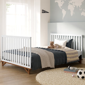 Kids bed with headboard and footboard in white color with natural wood accents, in bedroom setting, surrounded by various decorative items including soccer ball, baseball, books, headphone, and wall pennant