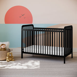 Black baby crib in nursery bedroom setting against wallpaper with geometric sunshine and beach shapes