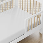 storkcraft pasadena white with driftwood toddler bed closeup of guardrail and headboard on wood floor