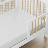 storkcraft pasadena white with driftwood toddler bed closeup of guardrail and headboard on wood floor