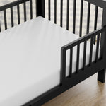 storkcraft pasadena black toddler bed closeup of guardrail and headboard on wood floor