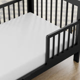 storkcraft pasadena black toddler bed closeup of guardrail and headboard on wood floor