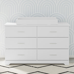 white changing topper on top of 6 drawer dresser in nursery 