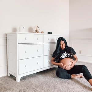 Angled view of white 6 drawer dresser in nursery with expecting mother