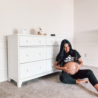 Angled view of white 6 drawer dresser in nursery with expecting mother