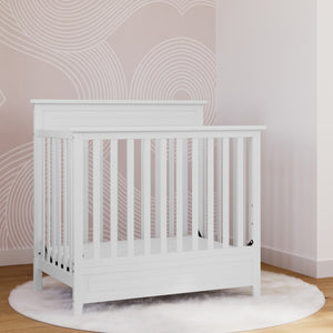 White mini crib in nursery 
