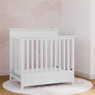 White mini crib in nursery 