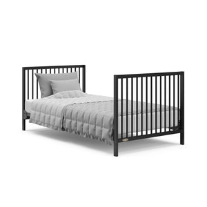 black mini crib in full-size bed with headboard and footboard