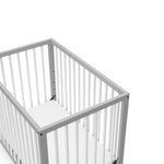 close-up view of pebble gray with white mini crib's headboard