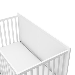 close-up view of white crib with drawer's headboard