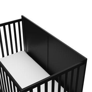 close-up view of black crib with drawer's headboard
