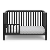 Black crib in toddler bed conversion with one safety guardrail