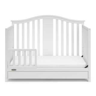 White crib with drawer in toddler bed conversion with one safety guardrail