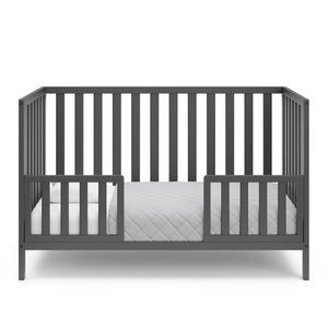 gray crib in toddler bed conversion with two safety guardrails