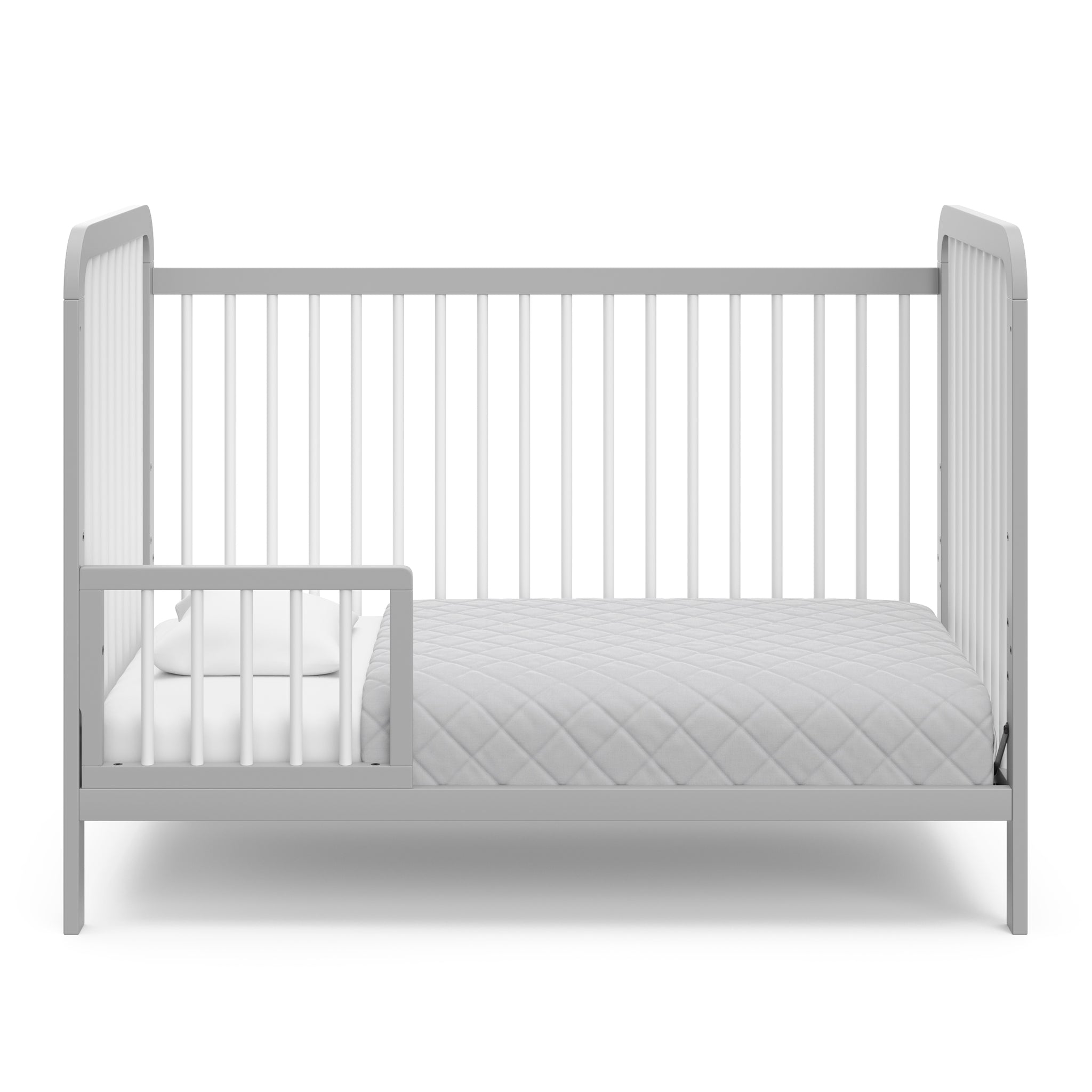 White crib with pebble gray in toddler bed conversion with one safety guardrail 