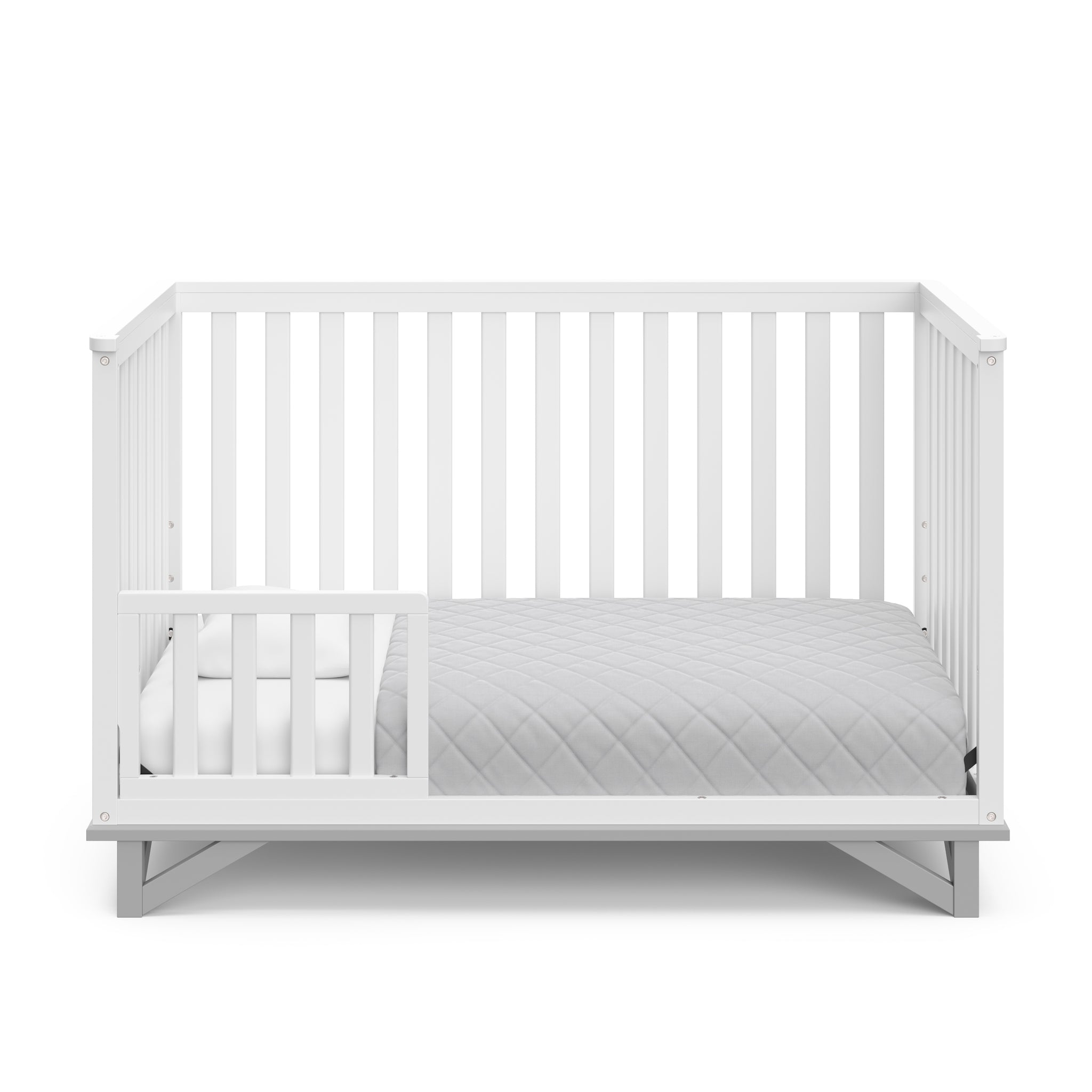 White crib with pebble gray in toddler bed conversion with one safety guardrail 