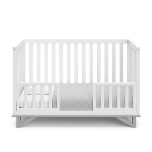 White crib with pebble gray in toddler bed conversion with two safety guardrails 