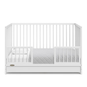 White crib with drawer in toddler bed conversion with two safety guardrails