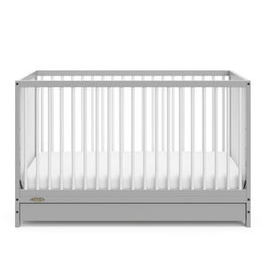 Front view of Pebble gray crib with open drawer
