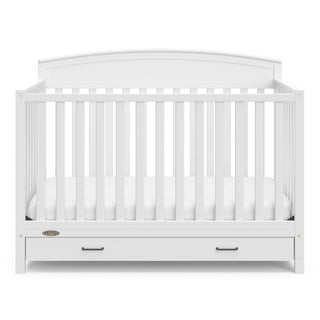 Front view of white crib with drawer