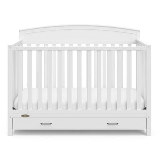 Front view of white crib with drawer