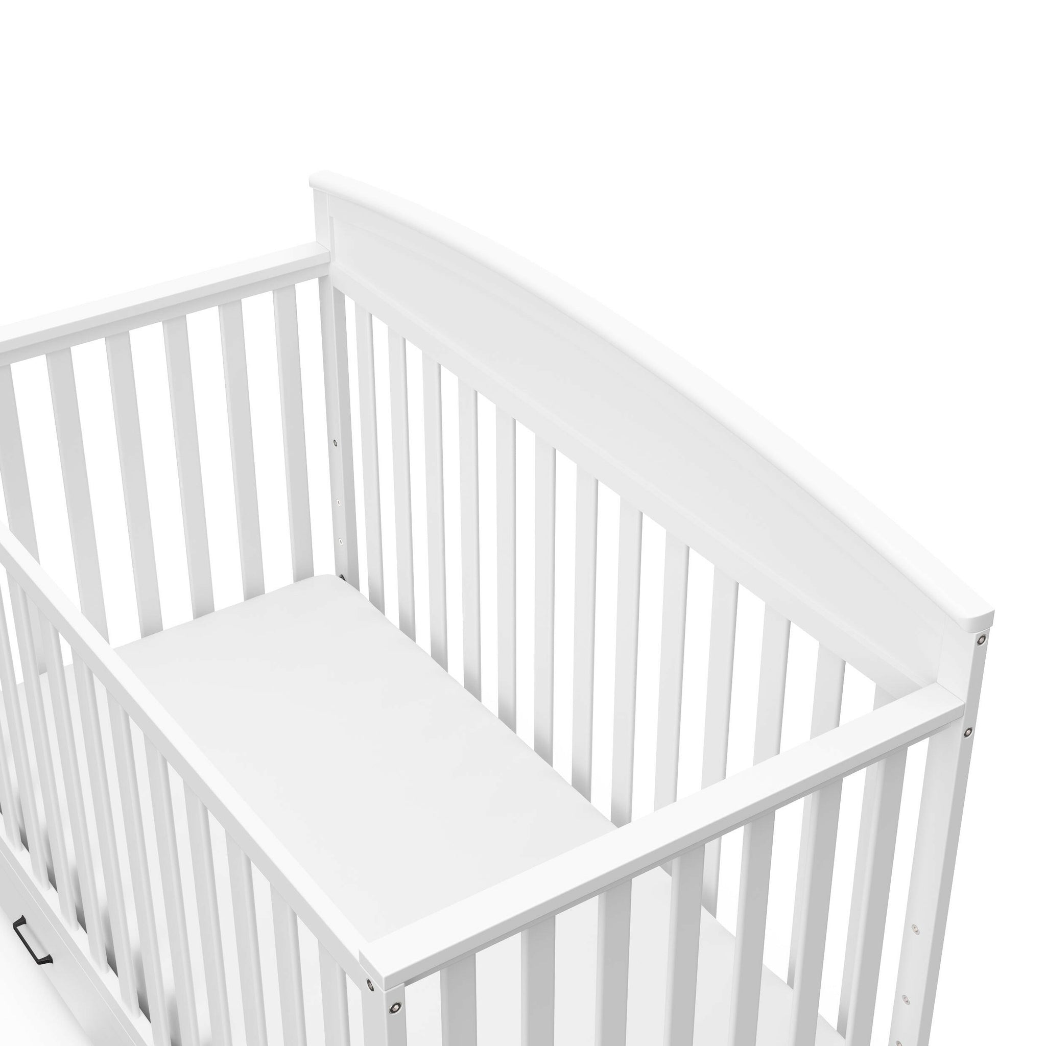 Close-up view of white crib with drawer