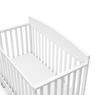 Close-up view of white crib with drawer