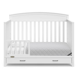 White crib with drawer in toddler bed conversion with one safety guardrail