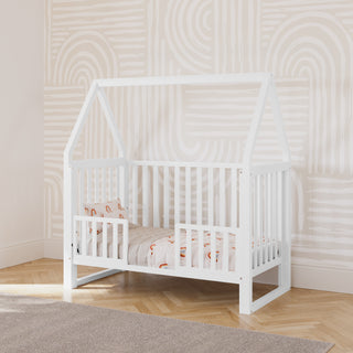 white convertible canopy crib in toddler bed conversion with two toddler safety guardrails, in nursery
