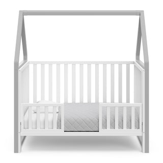 White crib with pebble gray in toddler bed conversion with two safety guardrails 