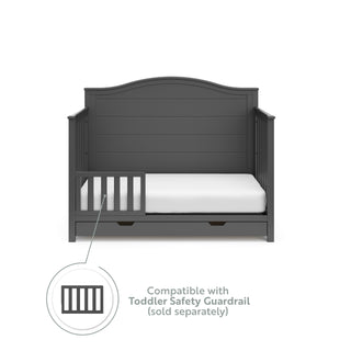 gray crib with drawer in toddler bed conversion with one safety guardrail graphic