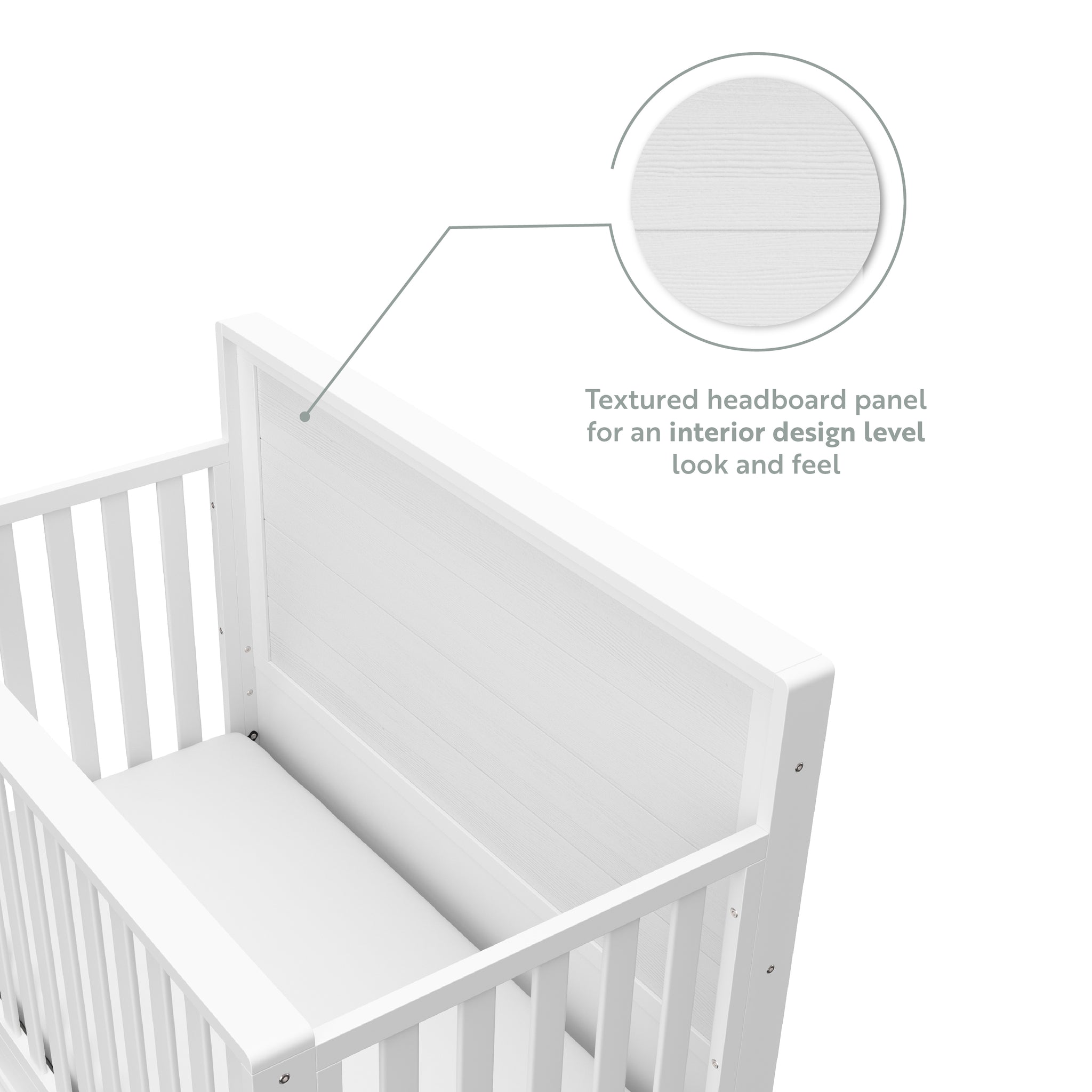 Close-up view of white crib with drawer headboard graphic