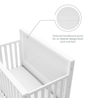 Close-up view of white crib with drawer headboard graphic