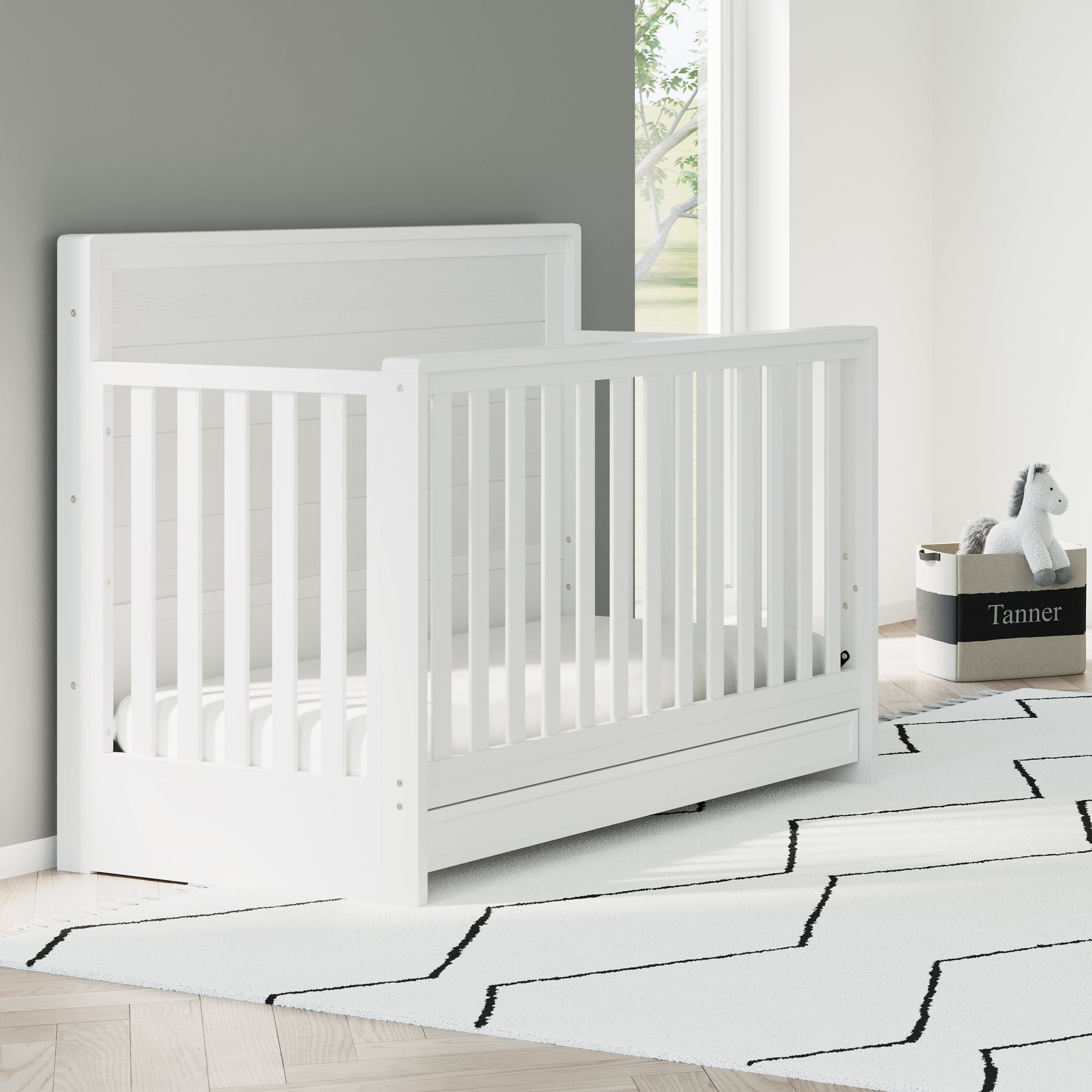 White crib with drawer angled in nursery
