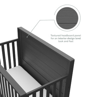 Close-up view of gray crib with drawer headboard graphic
