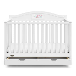 Front view of white crib with open drawer