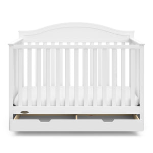 Front view of white crib with open drawer